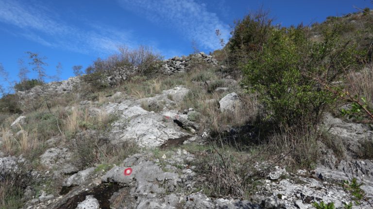 Rote Punkte führen zu einer Steinmauer hinauf.