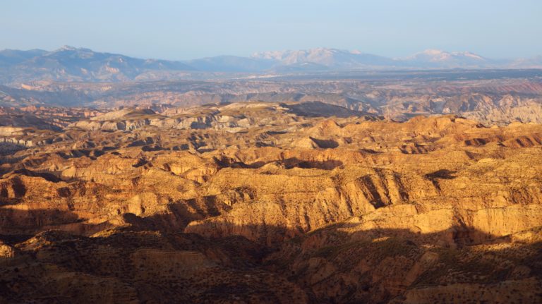 Die Badlands der Desierto de Gorafe im Abendlicht. Im Hintergrund die Berge der Sierra de Cazorla.