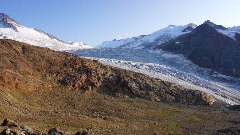 Um auf den Gletscher zu gelangen, steigt man in den Geröllkessel ab (Wegspuren) und überquert den Felsbuckel (Steinmännchen)