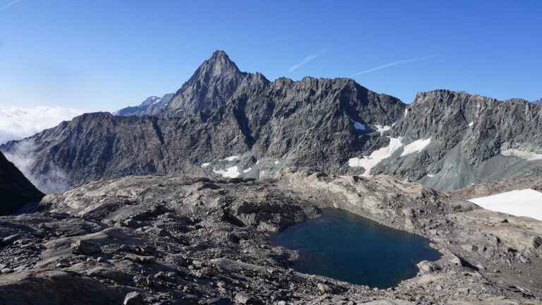 Das Seelein auf den Gletscherschliffplatten. Im Hintergrund die Bessanese.