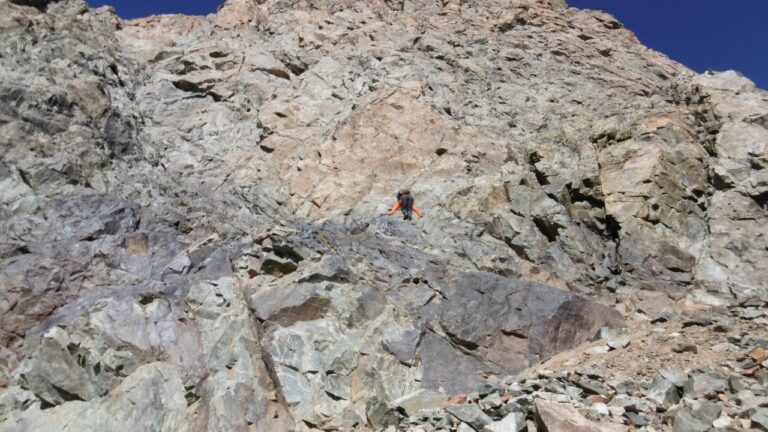 Entweder man klettert über die Felsrampe im Vordergrund, bis man das Felsband erreicht, das zum Col du Monêtier führt, oder man umgeht die Kletterei links in steilem Geröll.